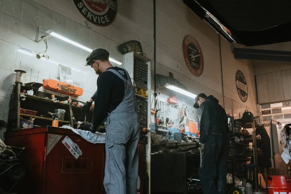 Two mechanics in a garage working on vehicle repair and maintenance.