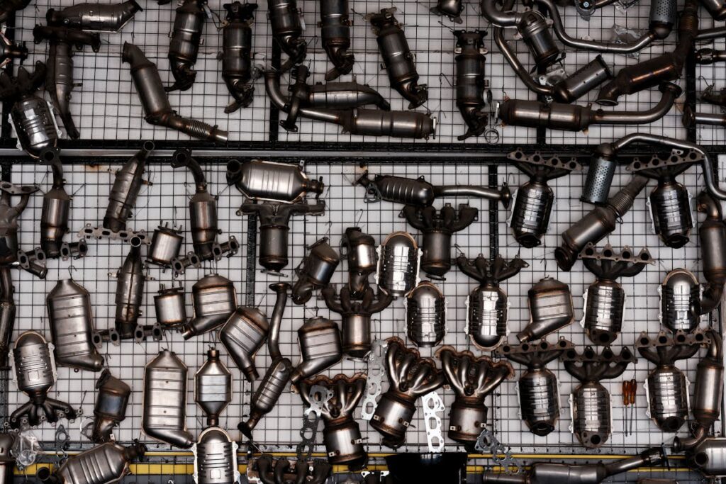An array of automotive exhaust parts displayed on a grid wall in an industrial garage setting.