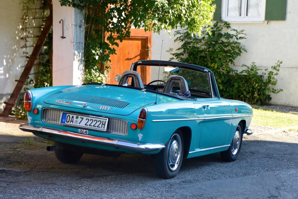 Classic turquoise Renault convertible parked in a sunny garden setting.