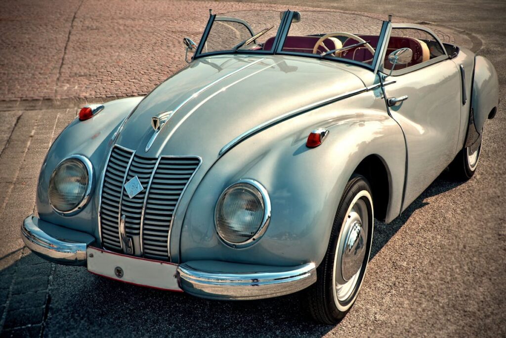A beautifully restored classic convertible car, featuring chrome details and vintage style, parked on a sunny day.