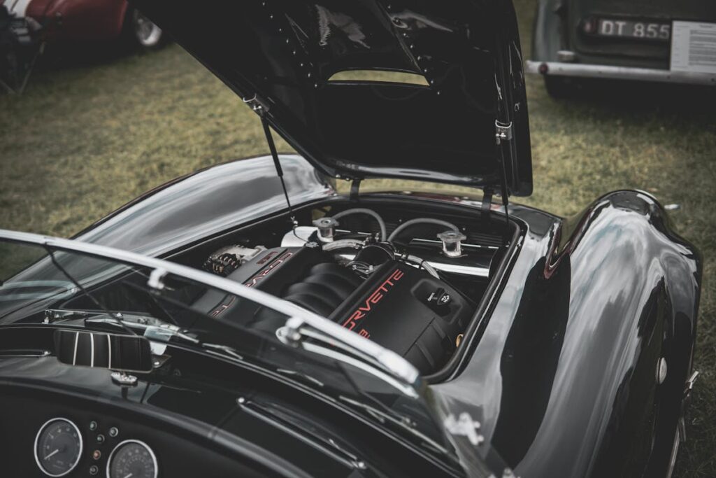 A classic sports car with an open hood revealing a Corvette engine in a vintage car show.