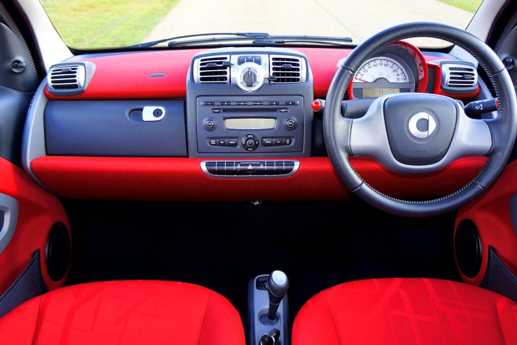 A luxury car interior showcasing a modern dashboard with red detailing, perfect for driving enthusiasts.