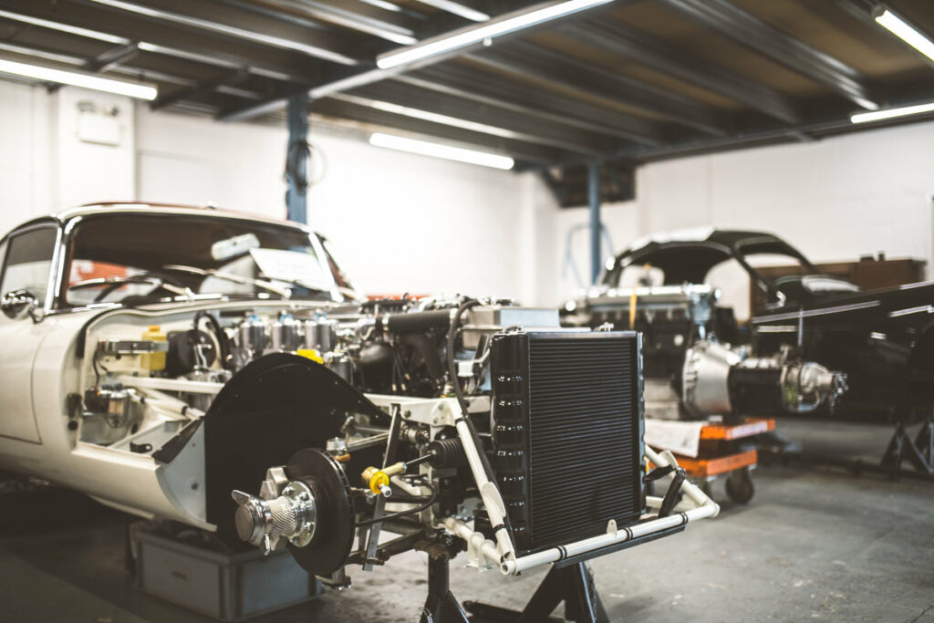A vintage automobile is disassembled in a garage, revealing its intricate mechanical components and frame for repair and maintenance