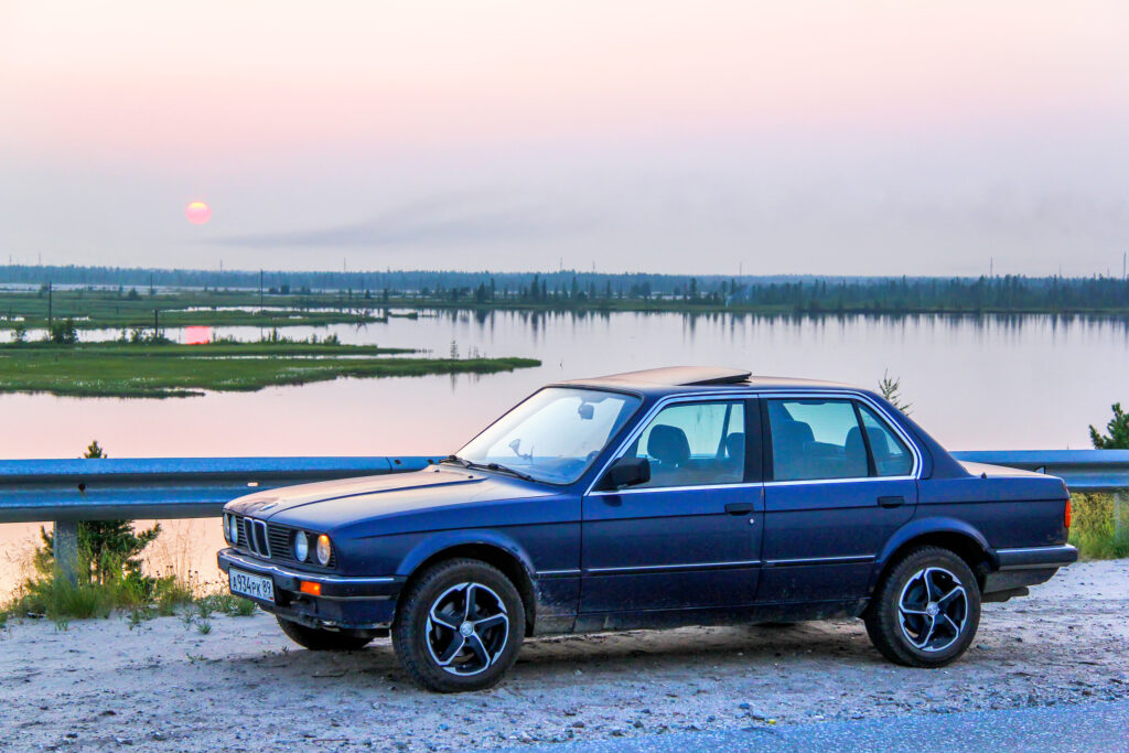 NOVYY URENGOY, RUSSIA - JULY 26, 2013: Motor car BMW E30 324d at the roadside at the background of the sunset.