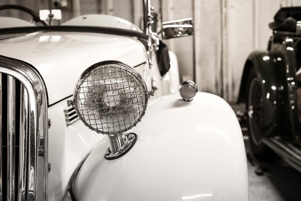 Classic white car in front view with detail on vintage style headlamp